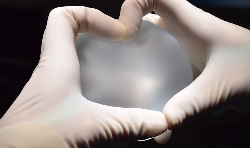 a person in white gloves holding a heart shaped object